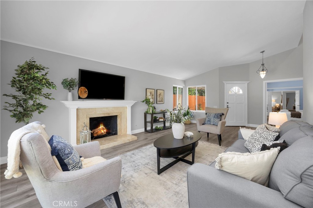 Vaulted living room at 3675 Cypress Ln with a tiled fireplace, light wood floors, and a sliding door to the backyard
