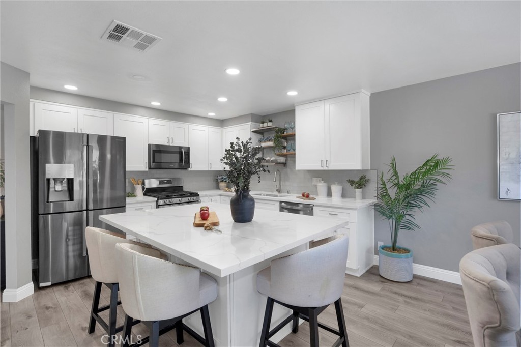Renovated kitchen with white shaker cabinets, stainless appliances, and a large white marble island