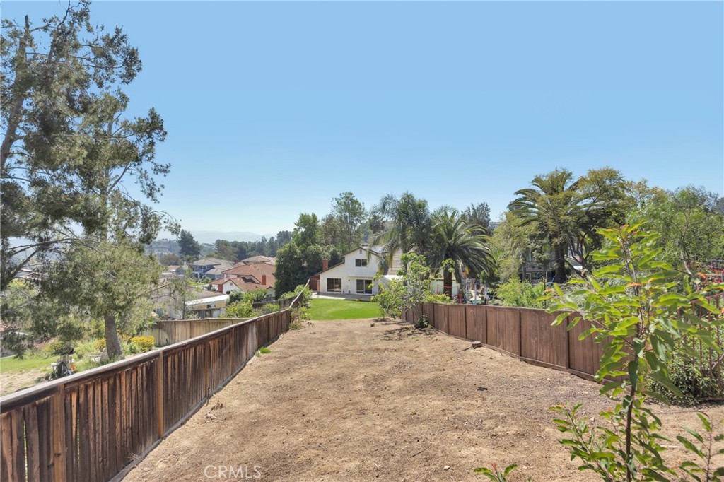 View from the rear of the 0.28-acre lot looking back at the house with rolling Yorba Linda hills and neighborhood beyond